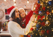 © Prostock-studio - Festive mother and daughter decorating Christmas tree at home