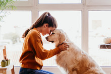 Close Up Of Beautiful Woman Hugging Her Adorable Golden Retriever Dog At Home. Love For Animals Concept. Lifestyle Indoors