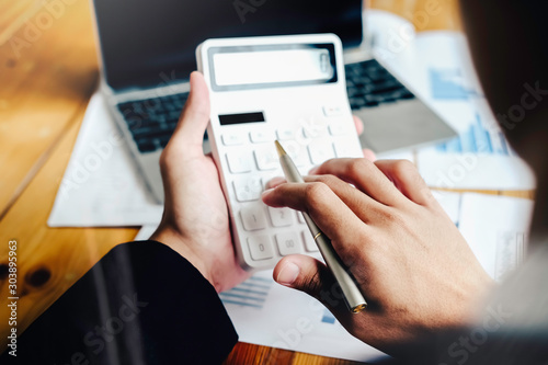 Fotografía asian businessman or accountant working pointing graph discussion and analysis data charts and graphs and using a calculator to calculate numbers