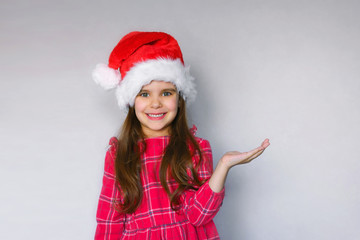 Wall Mural - happy funny child girl in red Christmas hat on gray background.