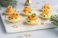 Canapes With Smoked Salmon, Cream Cheese And Avocado On Light Background With Space For Text. Christmas And New Year Holidays Background Concept. Starters Snacks Recipe Ideas.