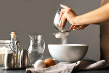 Woman Sieving Flour In Kitchen