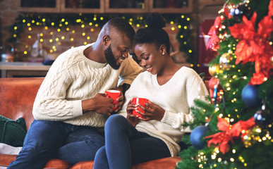 Wall Mural - Black couple celebrating Christmas together, reading coffee grounds for fun