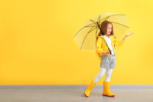 Fashionable Little Girl In Autumn Clothes And With Umbrella Near Color Wall