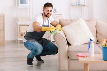 Poster - Male janitor cleaning furniture in room