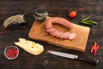 Wall Mural - Sliced cheese, sausage and bread on a wooden cutting board