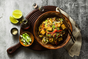 Wall Mural - Asian vegan stir fry with tofu, rice noodles and vegetables, top view.