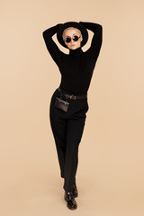 trendy hipster woman with blonde short hair wearing black stylish clothes, hat and sunglasses over b
