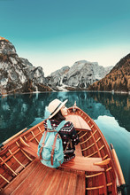Happy Asian Traveler Girl With Backpack Sitting In Vintage Wooden Boat At The Braies Lake In Dolomites Alps, Italy