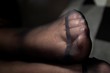A close up portrait of a foot in black nylon pantyhose with a reinforced toe. The details of the fabric are visible.
