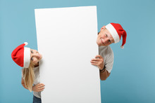 Smiling Young Santa Couple Friends Guy Girl In Christmas Hat Isolated On Blue Background. Happy New Year 2020 Celebration Holiday Concept. Mock Up Copy Space. Holding Big White Empty Blank Billboard.