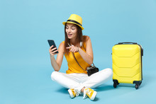 Traveler Tourist Woman In Yellow Casual Clothes, Hat With Suitcase Mobile Phone Isolated On Blue Background. Female Passenger Traveling Abroad To Travel On Weekends Getaway. Air Flight Journey Concept