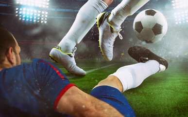 Football scene at night match with close up of two soccer players during a game match at the stadium