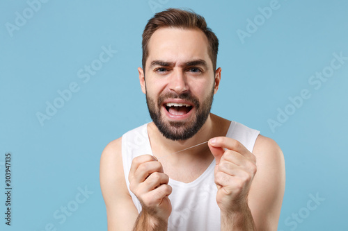 Bearded Young Man 20s Years Old In White Shirt Hold Using Dental Floss Isolated On Blue Pastel Wall Background Studio Portrait Skin Care Healthcare Cosmetic Procedures Concept Mock Up Copy Space