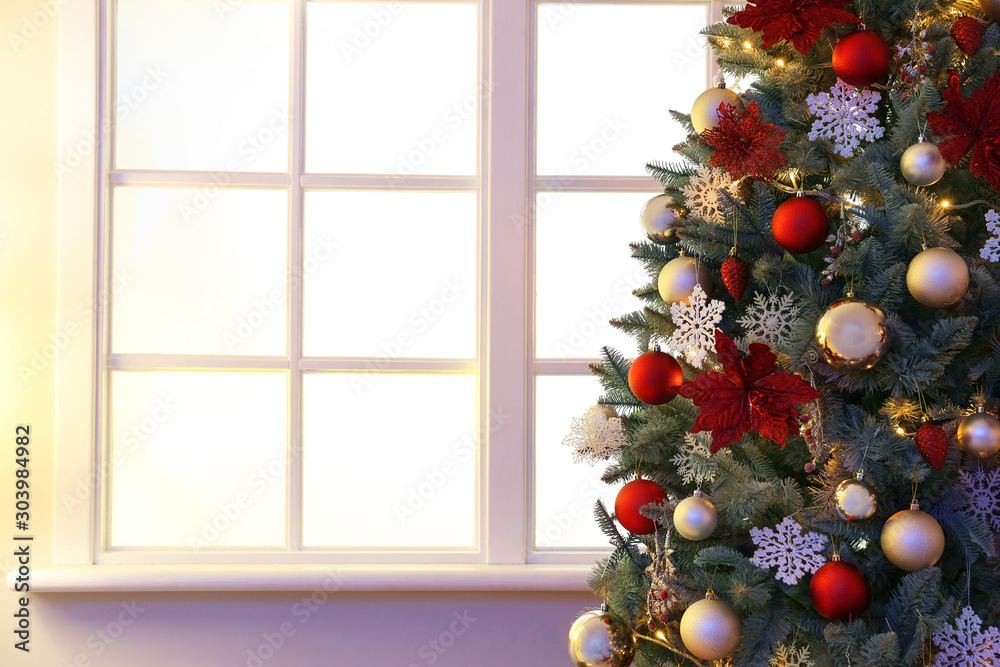Decorated Christmas tree near window in room