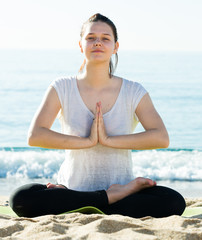 Wall Mural - Young girl in white T-shirt is sitting and doing meditation