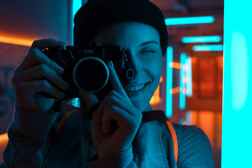 Canvas Print - smiling female photographer using camera in neon light