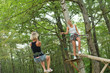© auremar - friends standing and keeping balance on rope in adventure park