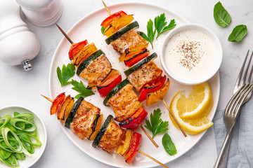 Grilled salmon and vegetables skewers on white plate