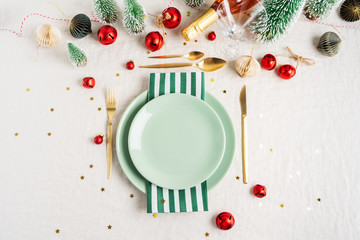 Christmas table setting. Holiday Decorations with vintage tree toys, shiny confetti, golden cutlery on light linen tablecloth with copy space. Holiday layout.