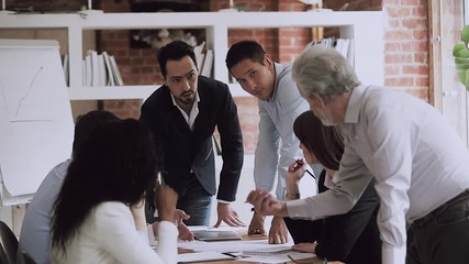 Wall Mural - Young and old colleagues disputing on paperwork at corporate briefing