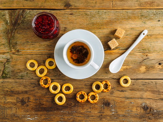 Herbal tea, raspberry jam and bagels on an old wooden table