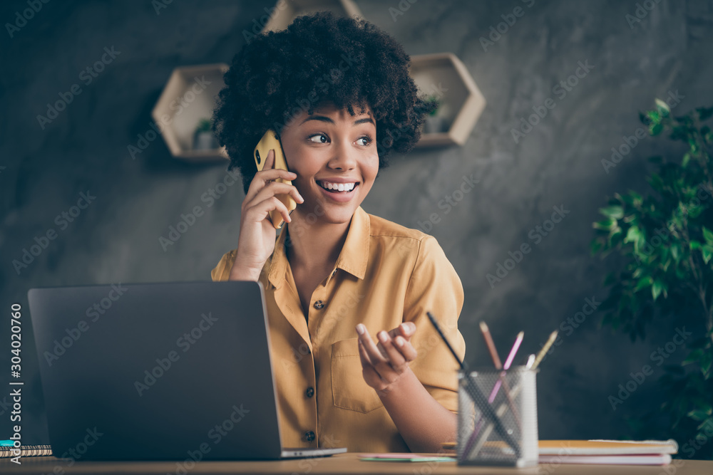 Photo of cheerful positive mixed-race pretty woman working as content manager arranging with her customers by phone smiling toothily - obrazy, fototapety, plakaty 