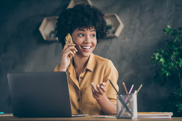 Wall Mural - Photo of cheerful positive mixed-race pretty woman working as content manager arranging with her customers by phone smiling toothily