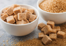 White Bowl Plates Of Natural Brown Sugar Cubes And Refined Sugar On Light Table Background.