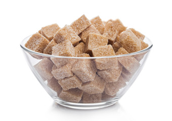 Wall Mural - Glass bowl of natural brown sugar cubes on white background.