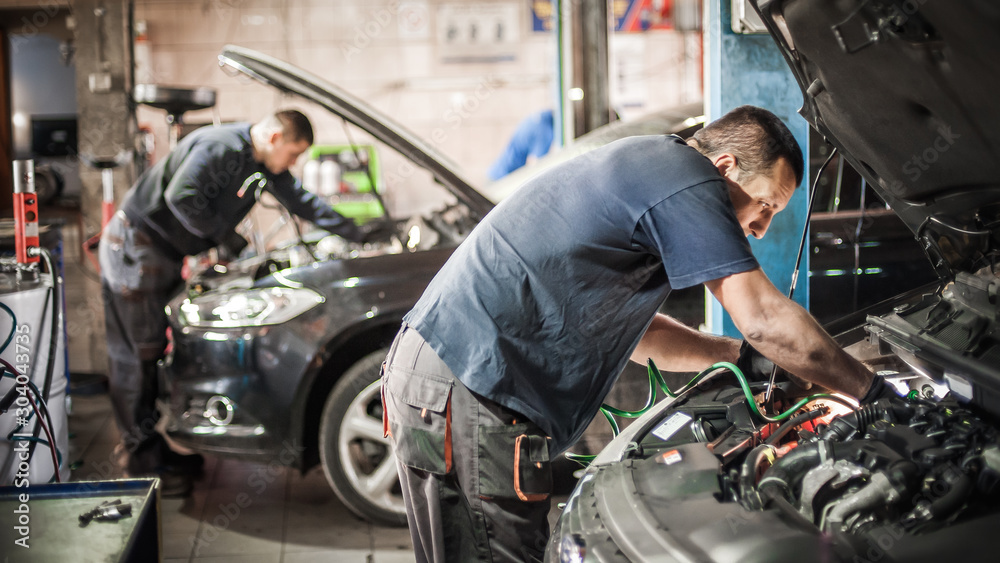 Car mechanic repairer service technician checks and repairs auto engine - obrazy, fototapety, plakaty 