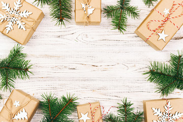 Christmas composition. Christmas gift, knitted blanket, pine cones, fir branches on wooden white background. Flat lay, top view. Toned