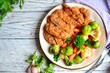 Chicken breast with vegetables. Baked chicken fillet, carrots, Brussels sprouts, broccoli, cauliflower. Food in a plate on a light wooden background.