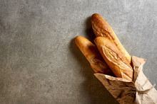 Fresh French Baguettes Packed In Paper On A Gray Stone Surface. Top View.