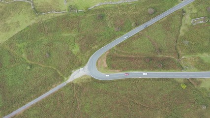 Wall Mural - Aerial drone view looking down onto traffic using a narrow, winding mountain road in a rural setting (Wales, UK)