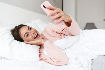 Poster - Cheerful lovely young girl wearing pajamas laying in bed