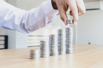 Saving money concept preset, the young man arranged the coins like a graph of the growing business, which made him have a driving force in his work.