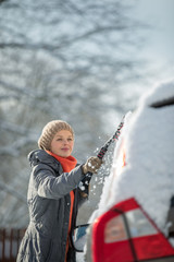 Wall Mural - Pretty, young woman cleaning her car from snow after heavy snowstorm (color toned image)