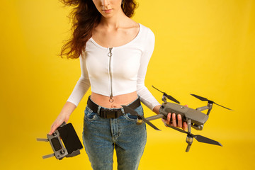 Teen girl launches aerial drone quadcopter. Isolated on a yellow background. Aerial photography.