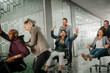 © JonoErasmus - Cheerful business people in smart casual wear having fun while racing on office chairs and smiling