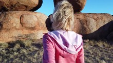 Hand In Hand Couple At Devils Marbles, Northern Territory: The Eggs Of Mythical Rainbow Serpent. Follow Me, Tourist Woman At Iconic Landscape Of Outback, One Of Australia's Most Famous Natural Wonders
