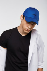 Wall Mural - Cropped front view shot of a dark-haired man, wearing blue baseball cap with lettering 