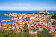 Beautiful Aerial View Of Historic City Center Of Ancient Piran With Famous Church Of Saint George And Tartini Square On A Sunny Day With Blue Sky And Clouds In Summer, Gulf Of Prian, Istria, Slovenia