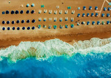 Fototapeta  - sandy beach with sun beds umbrellas in neat rows on the tsambika beach Rhodes Greece. The concept of a holiday resort view from drone