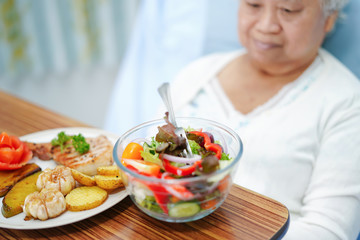 Asian senior or elderly old lady woman patient eating breakfast healthy food with hope and happy while sitting and hungry on bed in hospital..