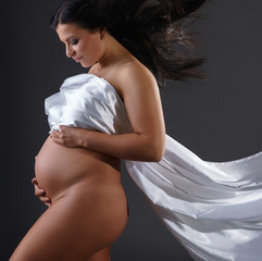 Naked pregnant woman posing with flying cloth