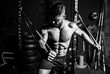 © Srdjan - Young sweaty strong focused fit muscular man chest stretching cross workout training in improvised gym with rubber for strength and good looking of muscles dark image black and white