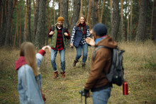 Group Of Friends On A Camping Or Hiking Trip In Autumn Day. Men And Women With Touristic Backpacks Going Throught The Forest, Talking, Laughting. Leisure Activity, Friendship, Weekend.