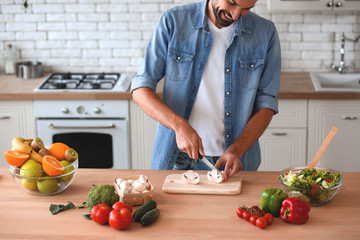 smiling man preparing salad at the kitchen