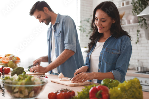 Fotomural smiling wife and husband cooking dinner in the kitchen together